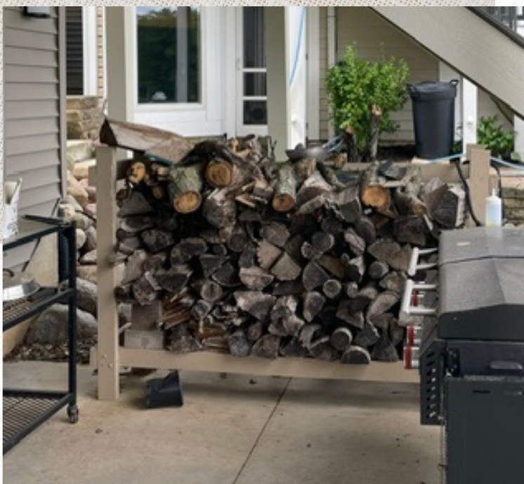 Original under-stair outdoor storage area with stacked firewood beside the residence