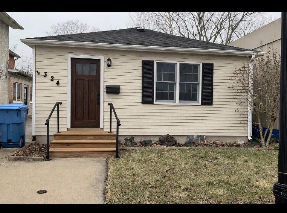 Existing Downtown rental property exterior with light siding, front windows, door and entry steps