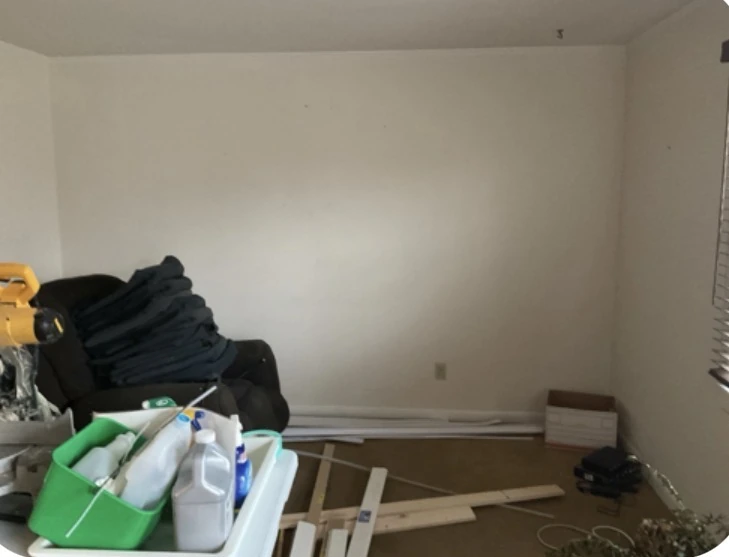 Existing rental living room with light walls, construction materials and furnishings during preparation