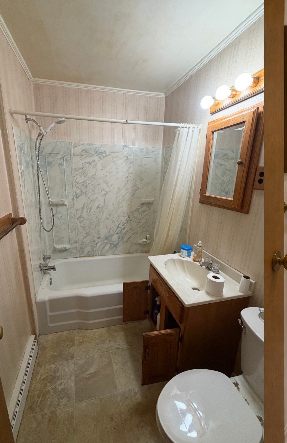 Original rental bathroom with bathtub, shower curtain, compact vanity and traditional finishes