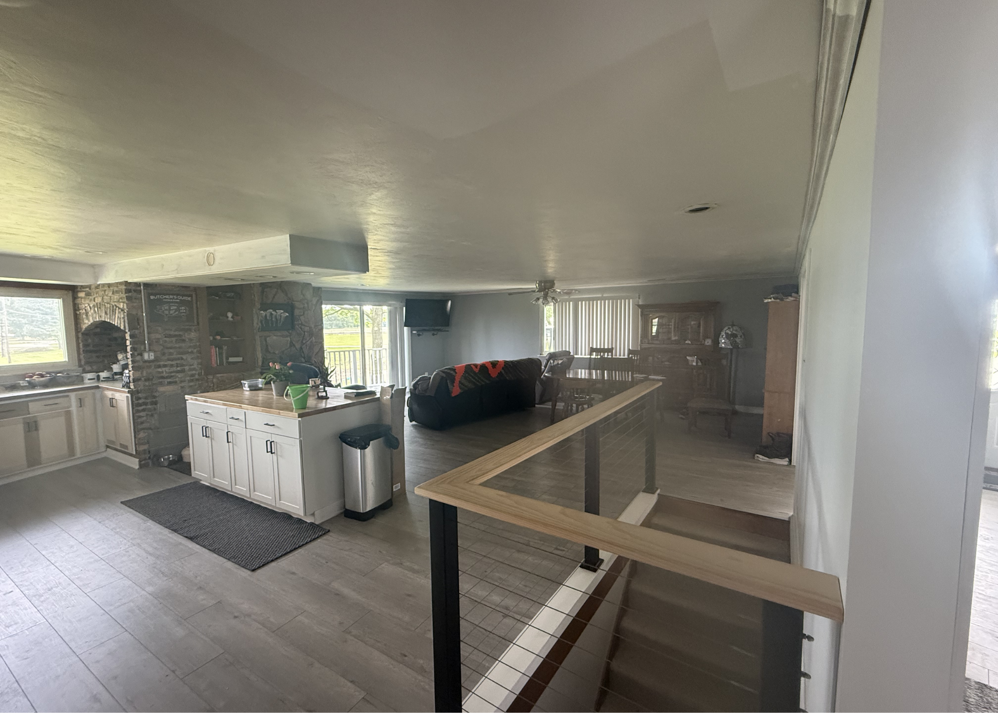 Original photograph of the open kitchen, island, stair railing, dining area and adjoining living room